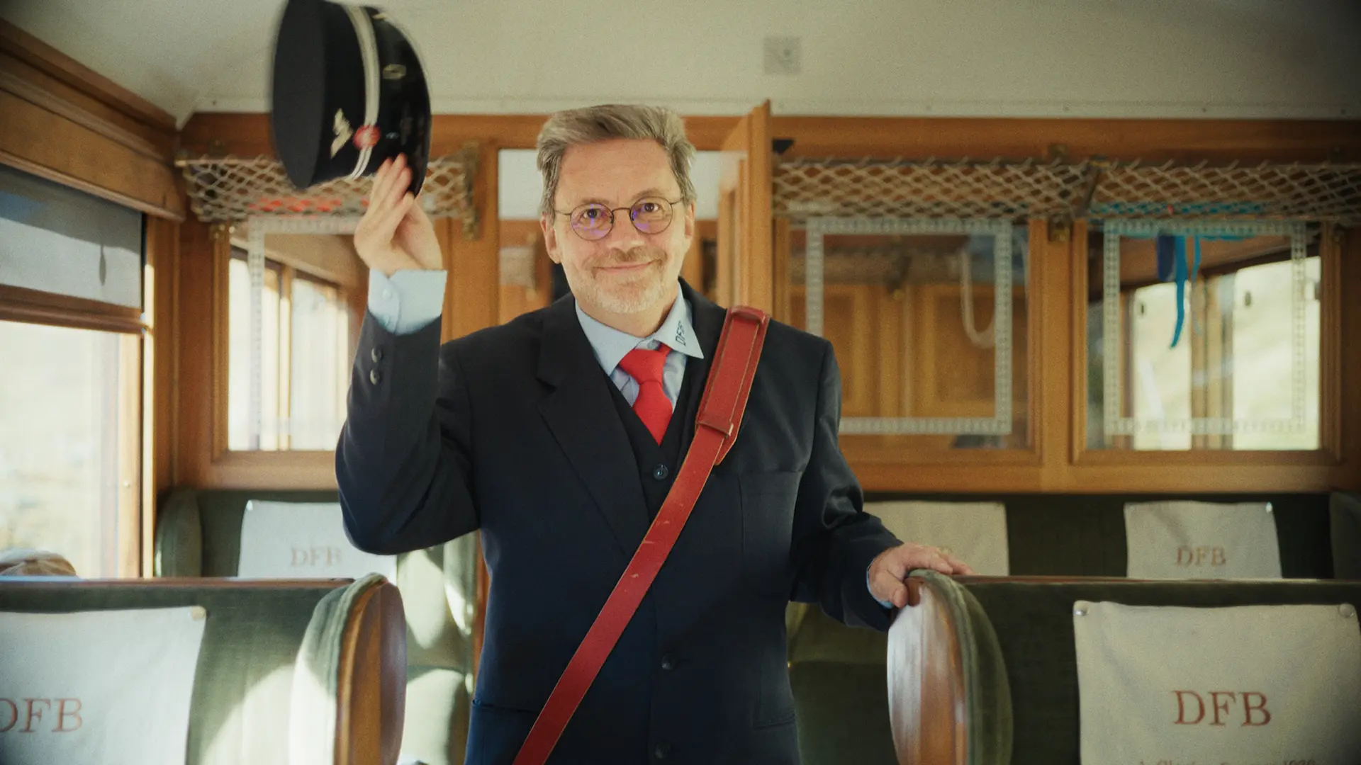 Schaffner grüsst mit Mütze im historischen Wagen